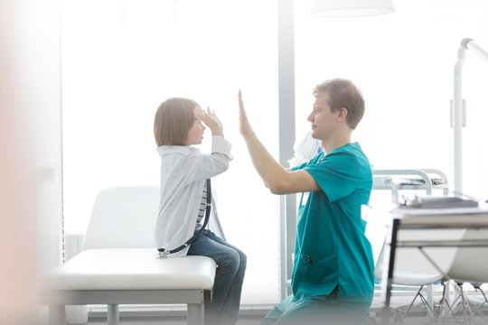 Nurse Giving Child Patient High Five In Clinic