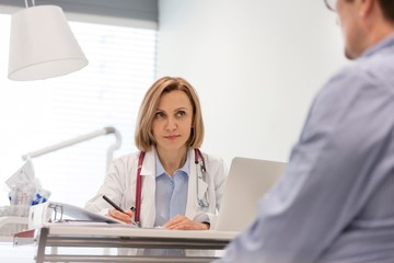 Fototapeta premium Doctor giving patient prescription in clinic