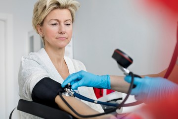 Nurse checking blood pressure of senior woman patient in clinic