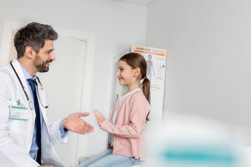 Obraz premium Pediatrician giving child patient high five in clinic
