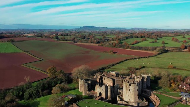 Aerial view of a large medieval castle showing the turrets, walls and moat (Raglan Castle, South Wales)