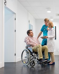 Obraz premium Doctor discussing medical result to patient sitting on wheel chair in clinic