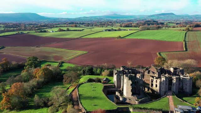 Aerial view of a large medieval castle showing the turrets, walls and moat (Raglan Castle, South Wales)
