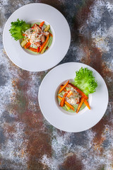 Salad with snow crab meat, avocado and vegetables. Two servings on a rusty background. Vertical shot