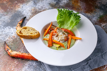 Close-up salad with snow crab meat, avocado and vegetables. Serving on a gray napkin and a rusty background