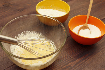 Making dough for baking from ingredients on a rustic wooden table.