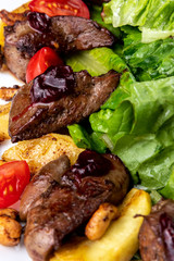 Food composition with liver salad and fried cashew. Arugula, tomato, potatoes on white plate. Macro view