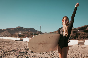 young woman standing with surfboard at Malibu beach. california lifestyle