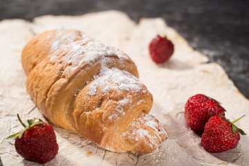 French croissant with strawberries. Rustic style, dark gray abstract background