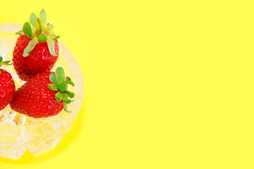 red natural fresh strawberries in a decorative glass plate on a yellow background