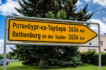 Russia, Vladimir Oblast, Golden Ring, Suzdal: Destination board to Rothenburg ob der Tauber, the twin city of the Russian town, in the city center with green tree and blue sky - travel friendship