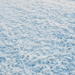 Snow covered frozen grass. White winter texture, top down view.