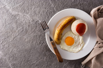 Arroz a la cubana.Typical Cuban rice with fried banana and fried egg on a plate on gray background. Top view. Copy space	