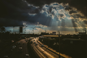 August 2019,Bangkok Thailand  Sun rays shining thru dramatic clouds scanning city of Bangkok below s.God message concept idea. Nature spiritual background. Traffic in city - Powered by Adobe