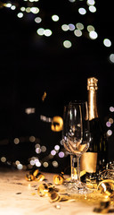New Year's Eve background with champagne bottle and glasses confetti and gold snakes New Year's Eve background with confetti and gold snakes on wooden table, lights