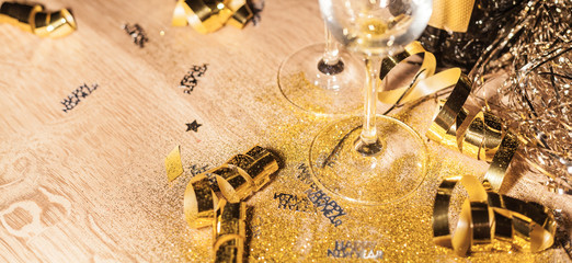 New Year's Eve background with champagne bottle and glasses confetti and gold snakes New Year's Eve background with confetti and gold snakes on wooden table, lights