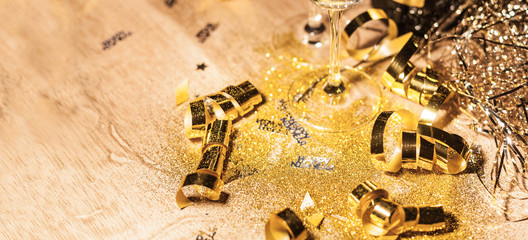 New Year's Eve background with champagne bottle and glasses confetti and gold snakes New Year's Eve background with confetti and gold snakes on wooden table, lights