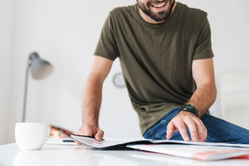 Cropped image of young smiling caucasian man reading documents