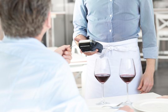 Mature customer paying through credit card at restaurant
