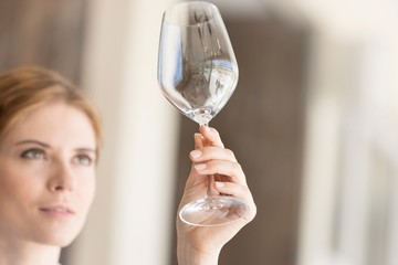 Closeup of young waitress looking at empty wineglass in restaurant