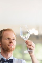 Closeup of young waiter looking at empty wineglass in restaurant