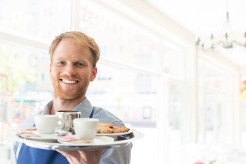 Portrait of confident young waiter serving espresso coffee at restaurant