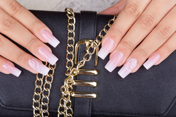 Hands with long artificial manicured nails with ombre gradient design in pink and white colors © natkinzu