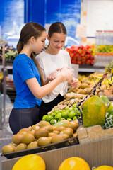 Teen girls shopping in supermarket reading product information. Choosing daily product