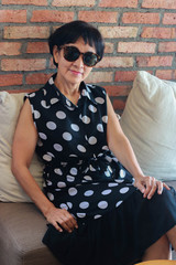 Asian senior woman sitting on couch and smiling