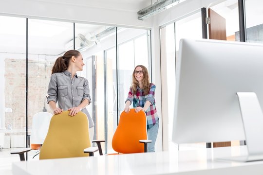 Young entrepreneurs moving chairs in office