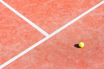 High angle view of tennis ball on red court during sunny day