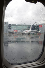 runway through the wet window of an airplane