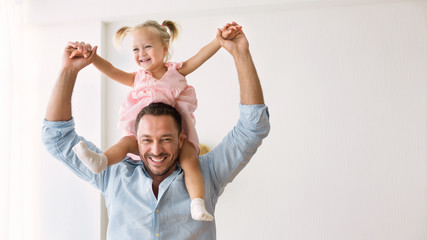 Millennial father riding his little daughter on shoulders