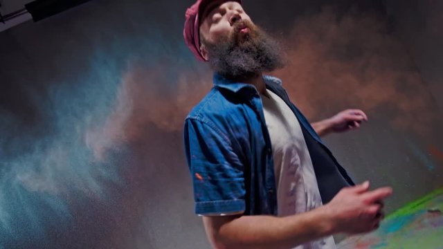 Man dancer showing break-dancing moves against colourful powder explosion