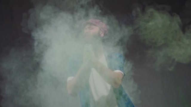 Man dancer showing break-dancing moves against colourful powder explosion.