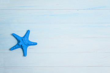 Fototapeta na wymiar Beach holidays concept. Blue starfish on the blue paint wooden background. Copy space