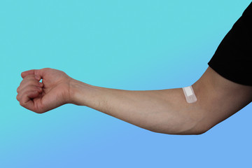 male hand sealed on the inside of the elbow with a medical plaster, concept intravenous injection, close-up
