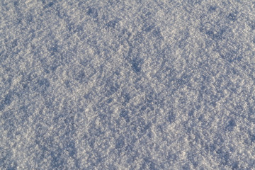 The texture of pure white snow. Close up of fresh clean snow with blue shadows.