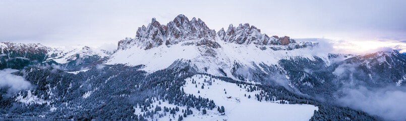 Scenic winter mountain landscape in Alps with aerial panoramic view of Geisler Peaks from Adolf Munkel trail in Zanser Alm, South Tyrol Dolomites with beautiful snow covered forest hills and summits