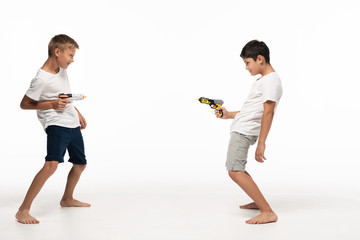 Naklejka premium two brothers aiming at each other with toy guns on white background