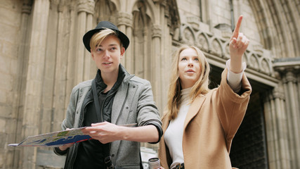 Two stylish friend standing at the street and look for something using a map