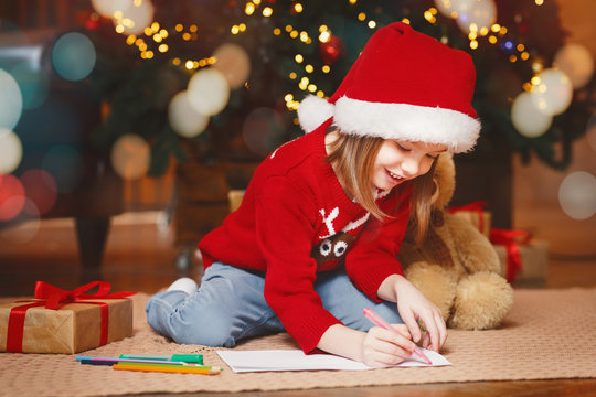 Cute little girl in red xmas hat writing letter to Santa