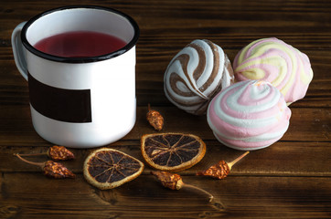 Colored marsmallow, dried oranges and fruit tea in metal cup