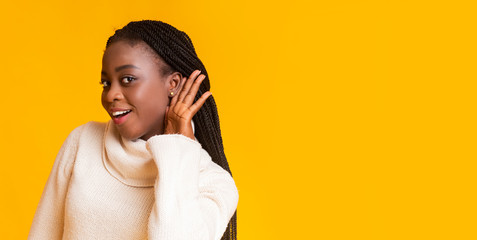 Curious african-american woman holding hand near ear