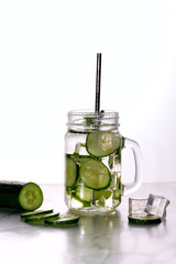 Glass of cucumber water with ice on white background.