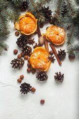 Tangerines without peel, Christmas tree branches, spices, cinnamon, cones on a white stone background. Concept of Christmas, New Year, Mulled Wine. Flat lay, top view