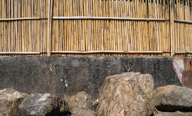Dry bamboo fence with a rocks. Eco natural background concept.