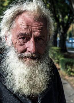 Close up portrait of old homeless alcoholic man face with white beard and hair wandering on the street depressed sick and lonely, social issues documentary concept