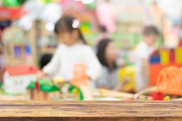Empty wooden table top on blurred child playing in playground background . Ready used us display or montage products design backdrop.