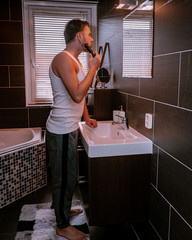 Close up portrait of a serious man shaving beard with an electric razor, Handsome young bearded man...
